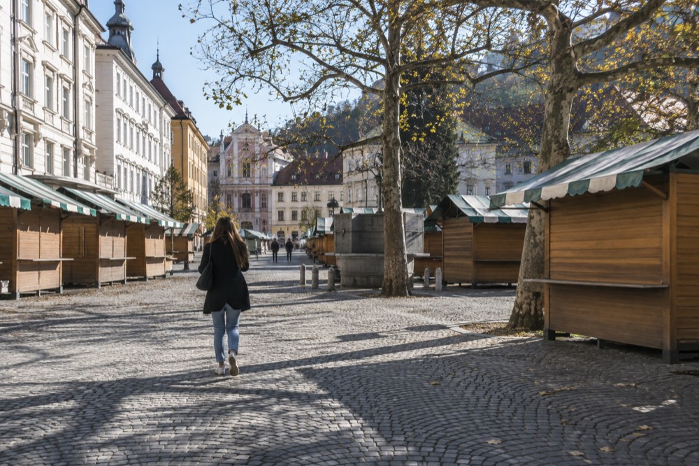 A quiet city square in morning light with closed shutters on the stalls around it