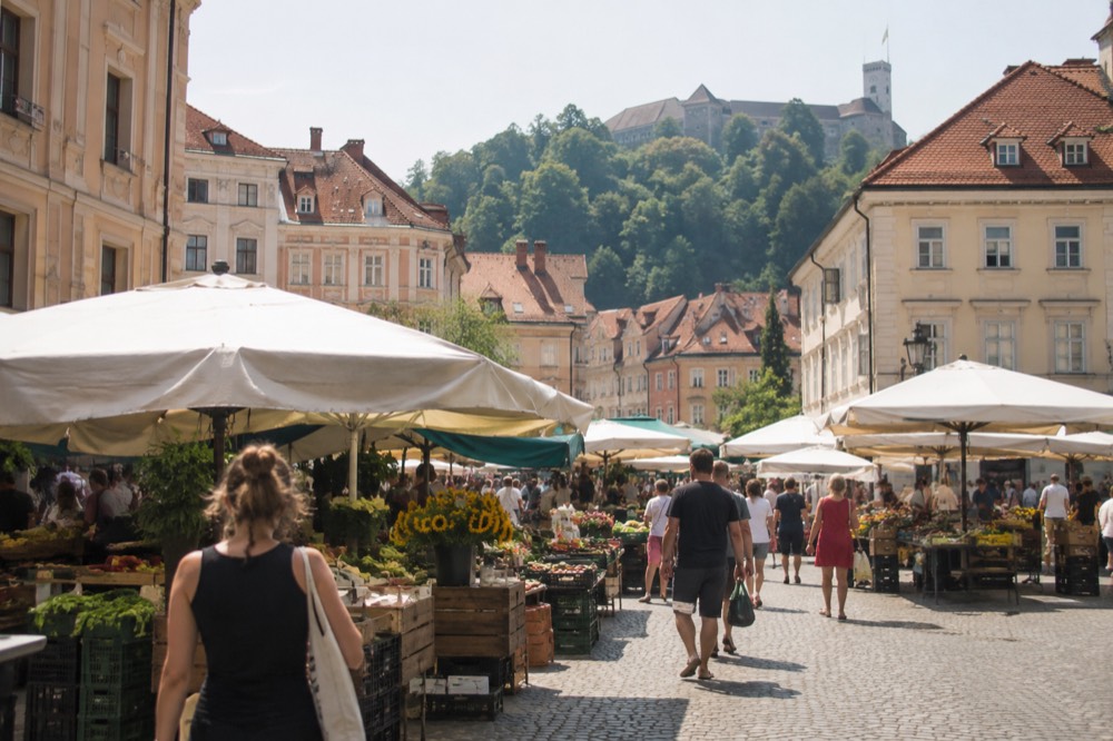 A busy outdoor food market with stalls and people browsing on a square in Ljubljana