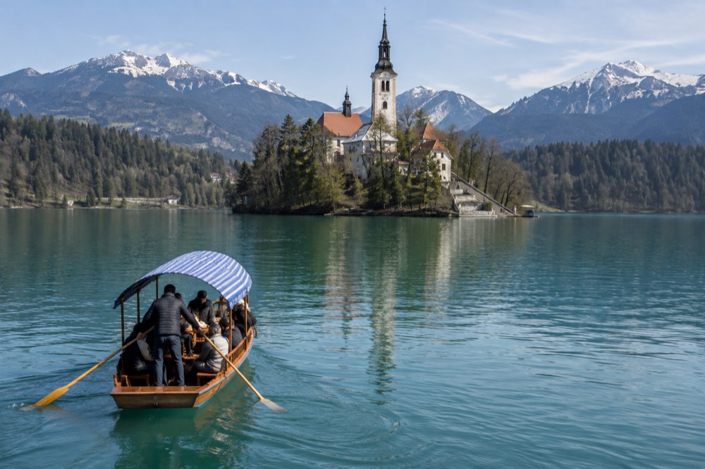 Wooden pletna boat on Lake Bled approaching the island church