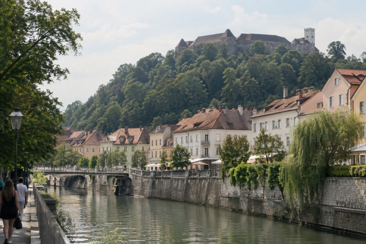 Pastel buildings along the Ljubljanica river in Ljubljana with the castle hill rising behind