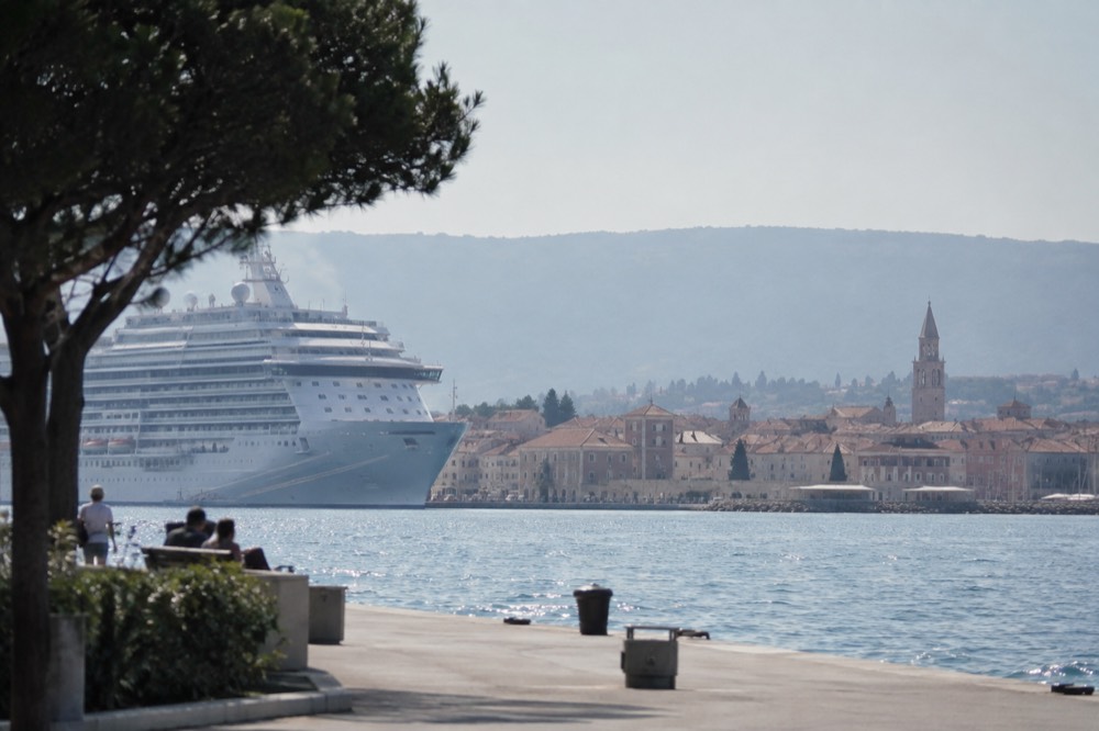 Koper: cruise ship docked at a coastal port with a historic town behind it