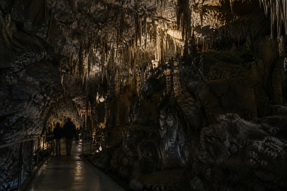 Cave interior with lit stalactite formations above a walkway