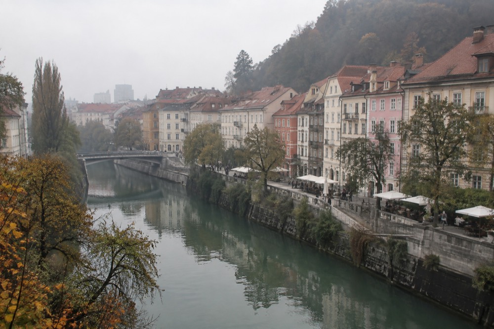 River promenade with tables and pastel facades along the water