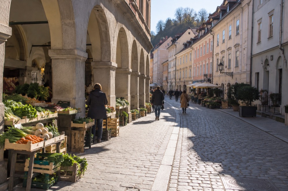 Market stalls with produce crates under stone arcades