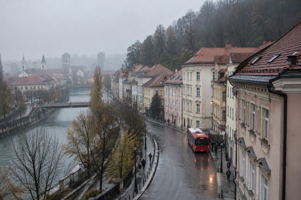 Red Ljubljana city bus at a stop on a wet street